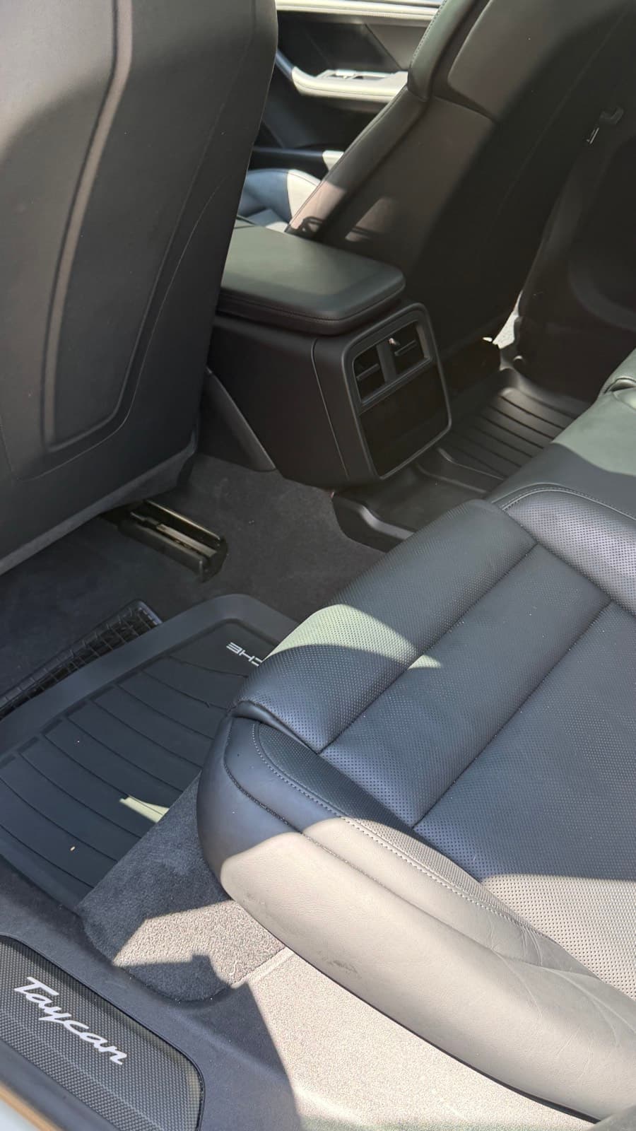 Detailed black leather rear seats and Porsche floor mats in a Porsche Taycan